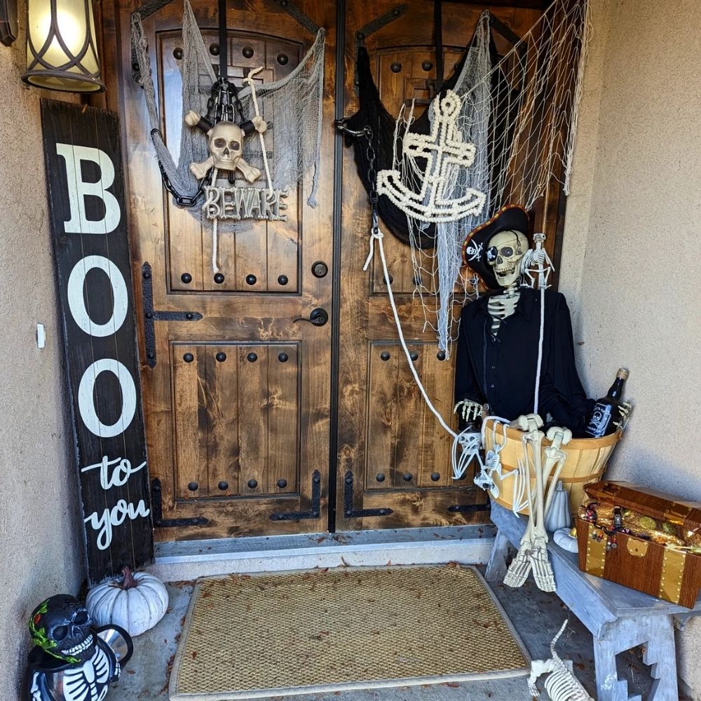 Halloween porch with a pirate skeleton, treasure chest, and BOO sign