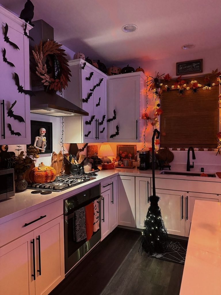 Moody kitchen with bats on the cabinets and a lit witch’s broom
