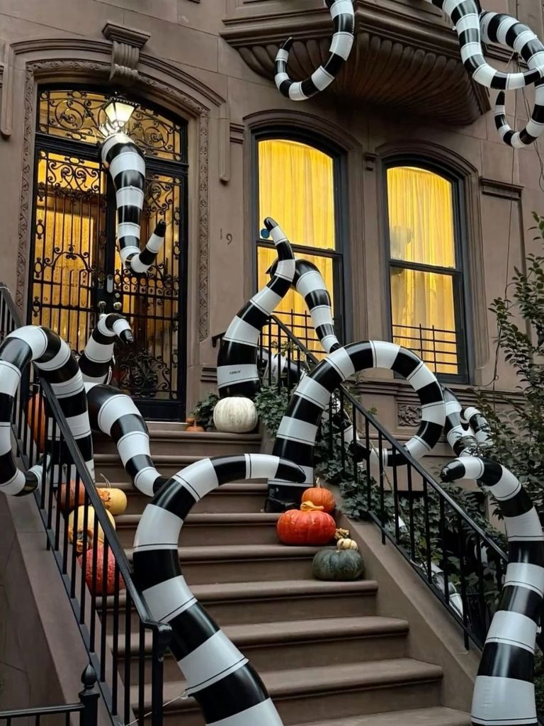 New York City stoop with Beetlejuice-inspired striped inflatable creatures and spiderwebs