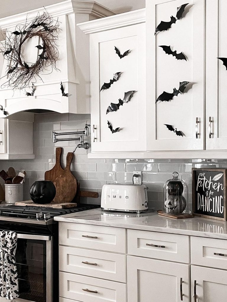 White kitchen cabinets decorated with black bats and a twig wreath