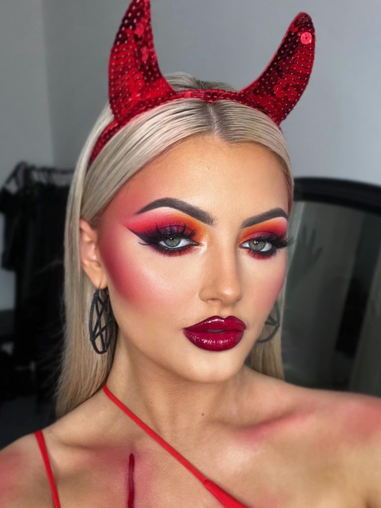 Fiery orange and red eyeshadow, a deep berry lip, and sequined devil horns create an easy Halloween makeup look.