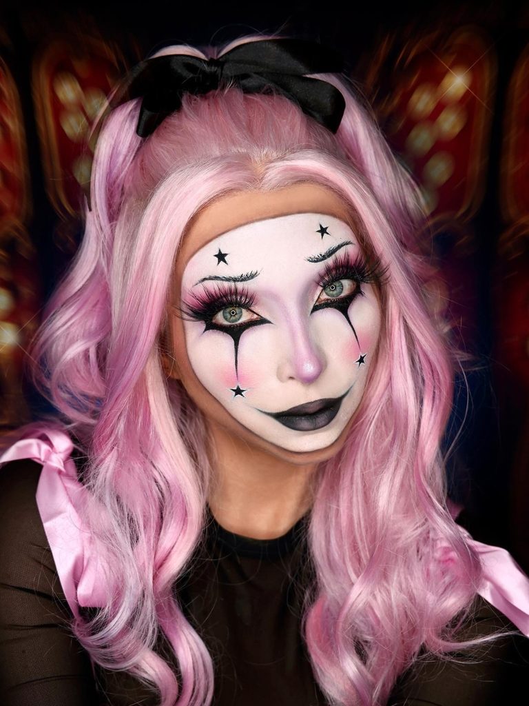 Pastel pink hair, porcelain-like skin, black star details, and a smoky black lip create a scary-cute clown look.