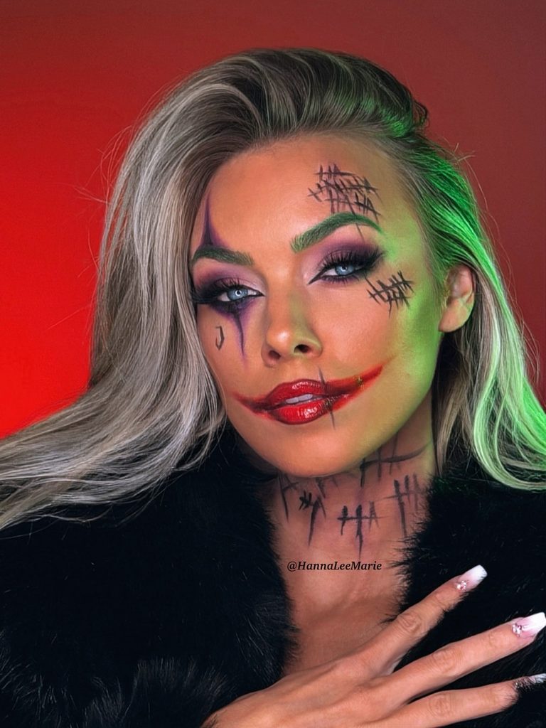 Purple winged eyeliner, a jagged red smile, and black painted details create this Joker-inspired clown makeup look.