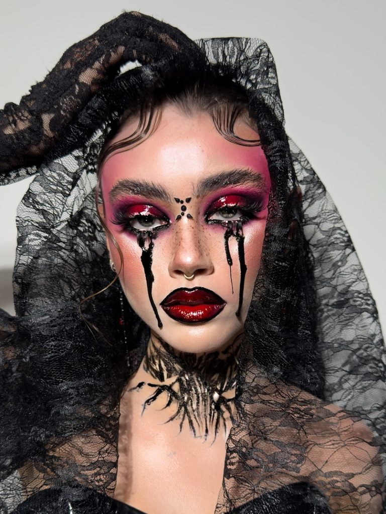 Deep red smoky eyes, long black tears, and a sheer black mourning veil create a dramatic gothic Halloween makeup look.