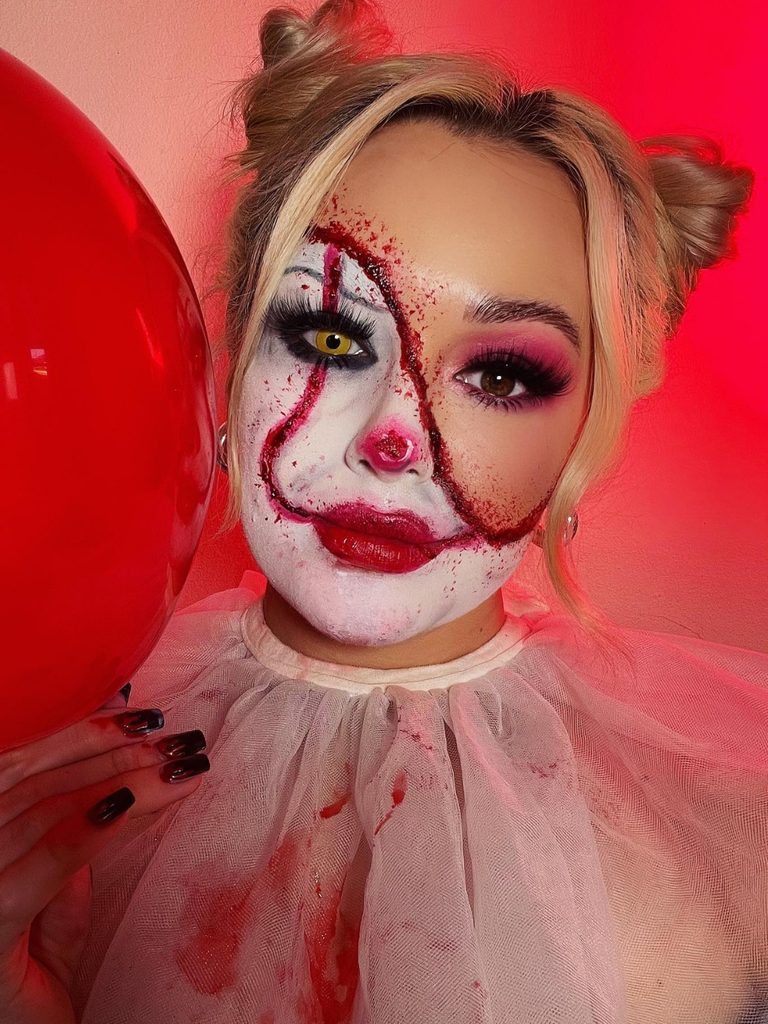 White face paint, a painted red grin, and a bulbous nose contrast with soft glam makeup in this split-face clown design.