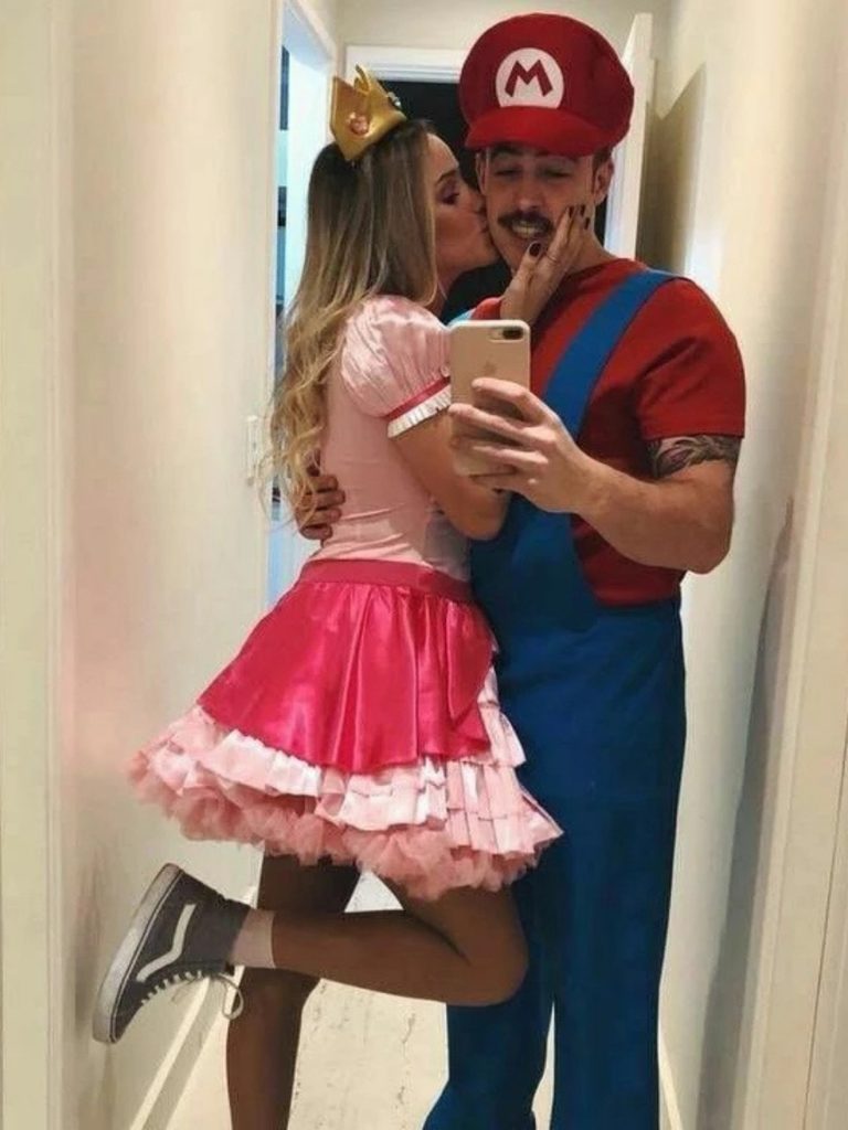 Couple dressed as Mario and Princess Peach in blue overalls and a pink skirt.
