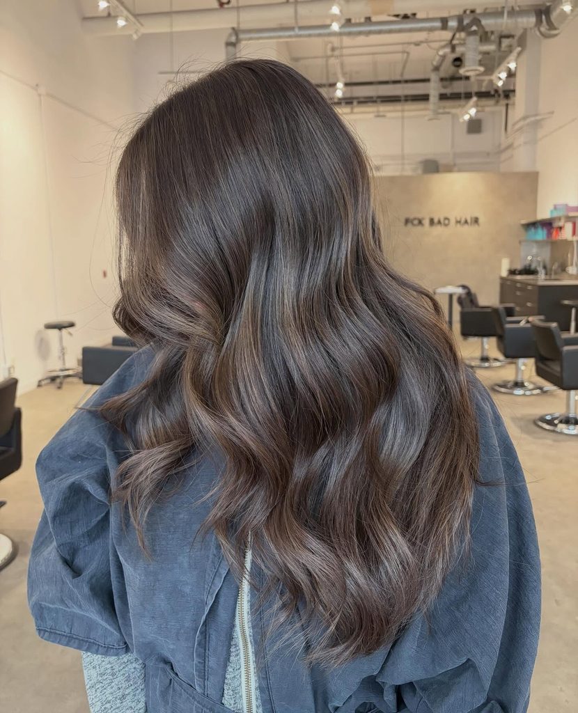Back view of long wavy teddy brown hair with soft caramel balayage, a warm neutral fall brown hair color.