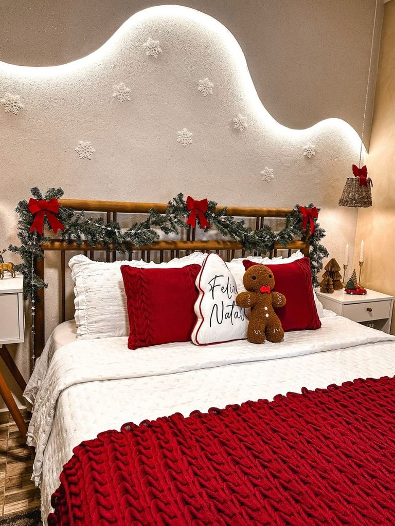 Christmas bedroom decor with garland and red bows on an iron bed, a cloud headboard, and a red knit blanket