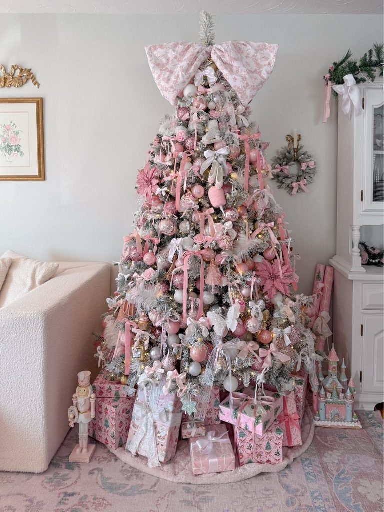 Pink flocked Christmas tree with a giant bow topper, ribbons, and pink wrapped gifts