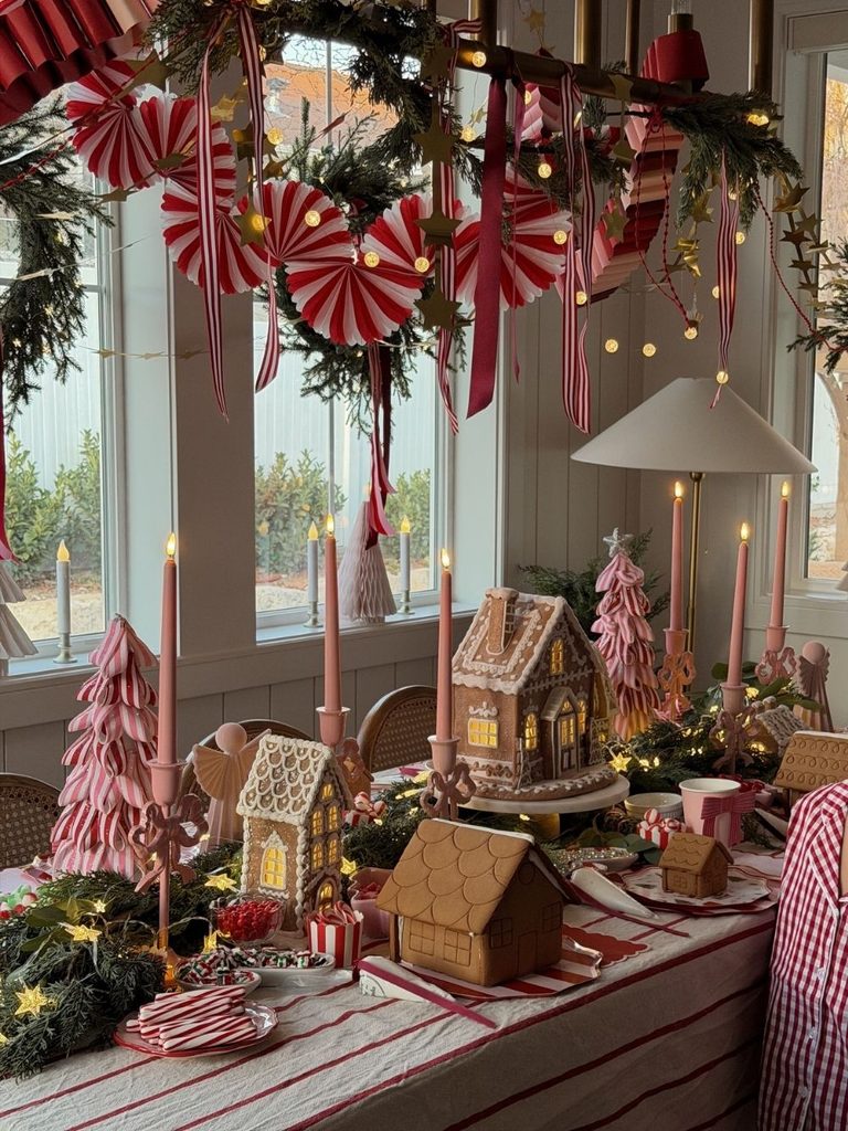 Striped table set up for decorating gingerbread houses with candy, pink trees