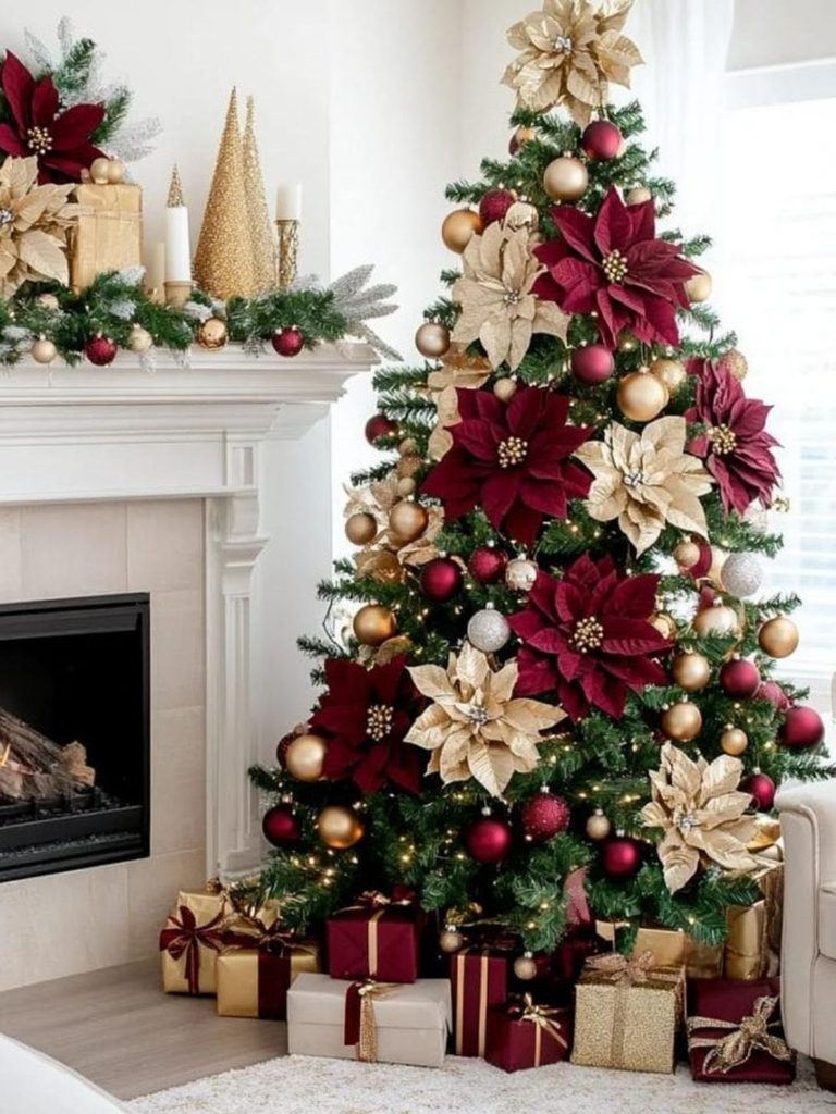 Christmas tree decorated with burgundy and cream poinsettias beside a fireplace and wrapped gifts