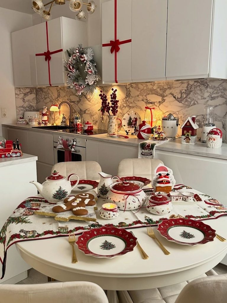 Round kitchen table with red and white Christmas dishes and upper cabinets tied with red ribbon bows