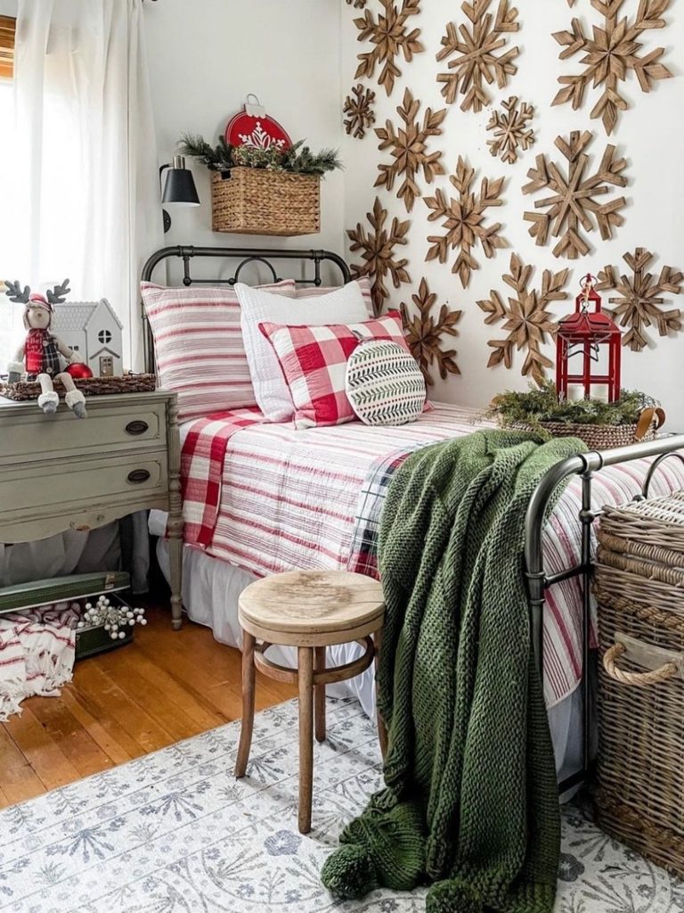 Bedroom with a wall of wooden snowflakes, an iron bed, red plaid bedding, and a green throw