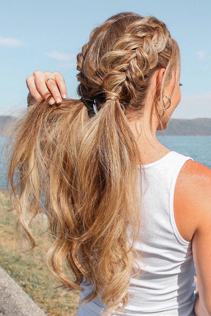 Double Dutch braids from the temples meeting in a low wavy ponytail by the water