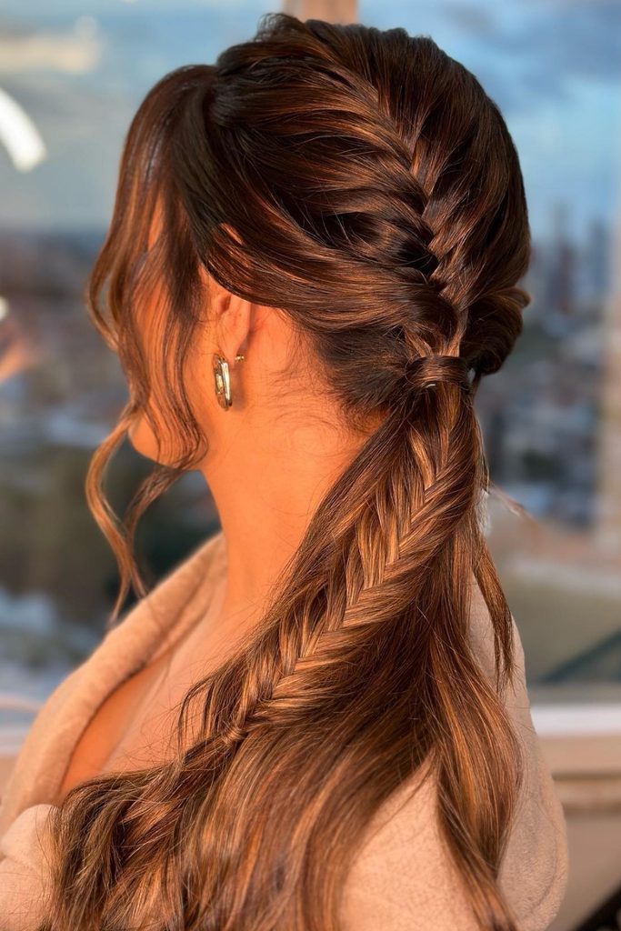 Textured French braid flowing into a loose low ponytail with face-framing pieces