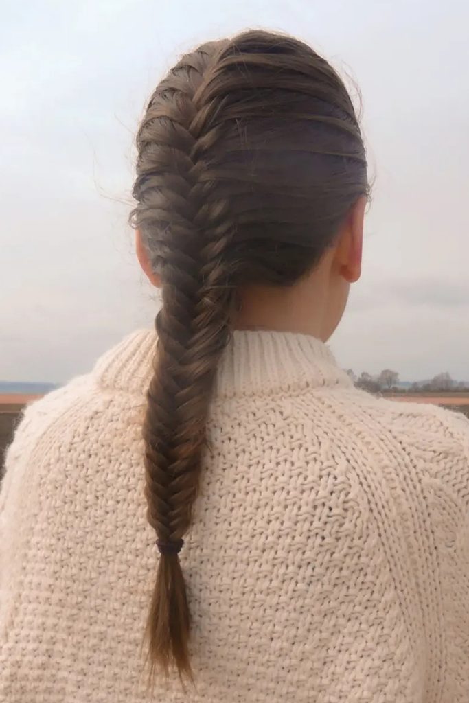 French fishtail braid worn with an oversized cream knit sweater