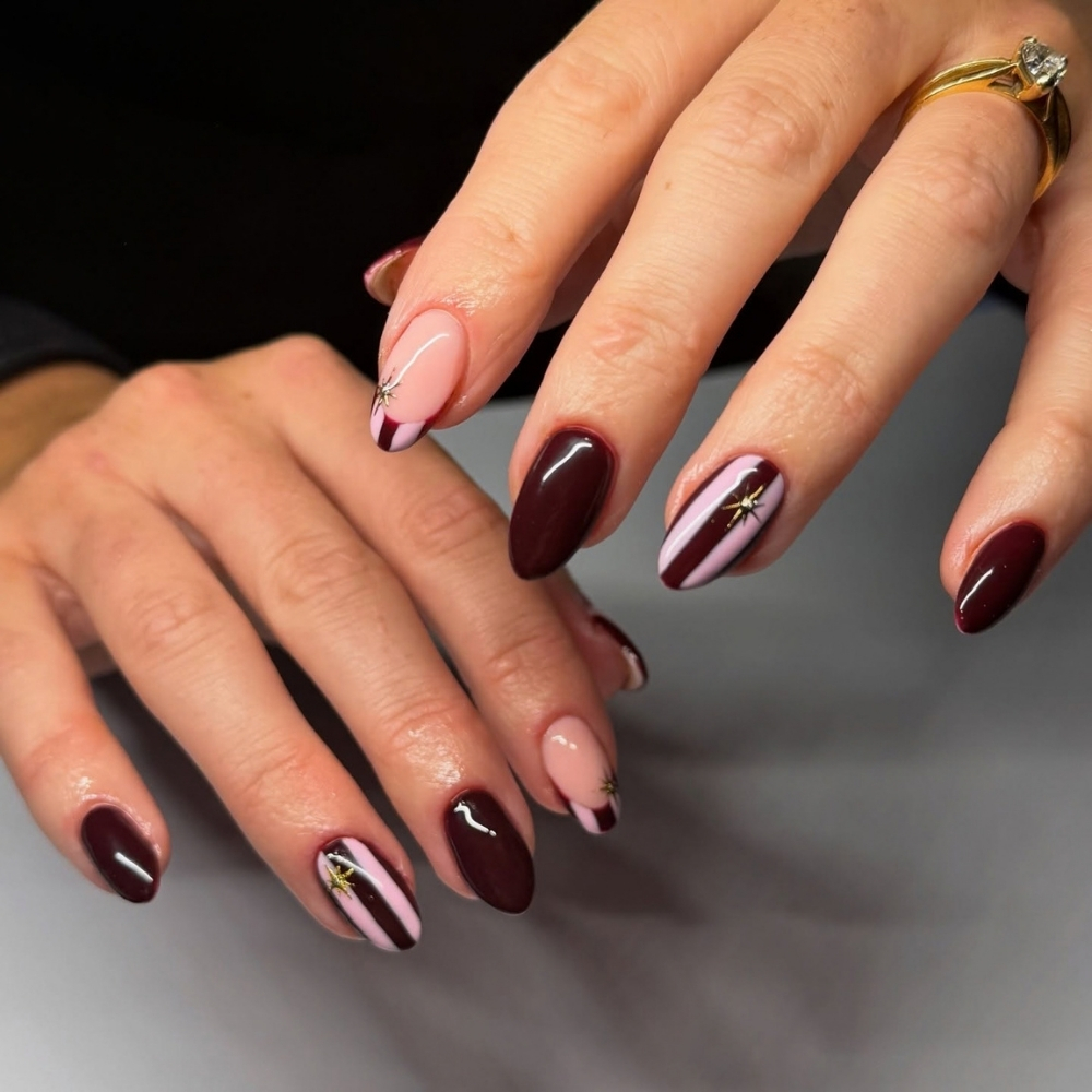 Oxblood burgundy nails with pink stripes and gold stars